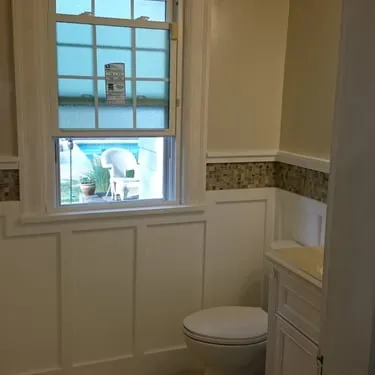 Bathroom with a window, wainscoting, toilet, and vanity