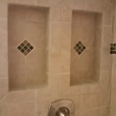 Tiled shower wall with recessed niches and decorative tile insets