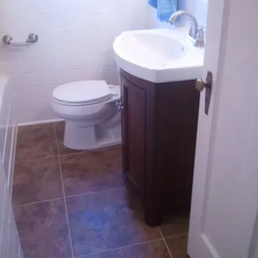 Bathroom with a dark wood vanity, toilet, and brown tile floor