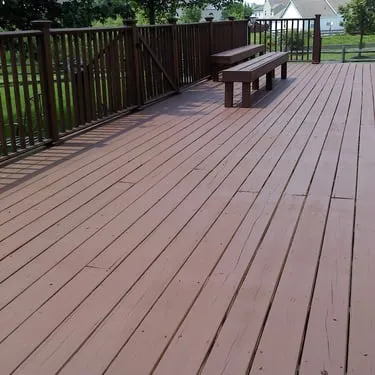 Broad wood deck with a built-in bench and dark railing