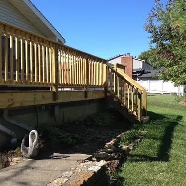 New pressure-treated wood deck with railings beside a home