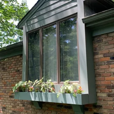 Window box mounted beneath a window on a brick home